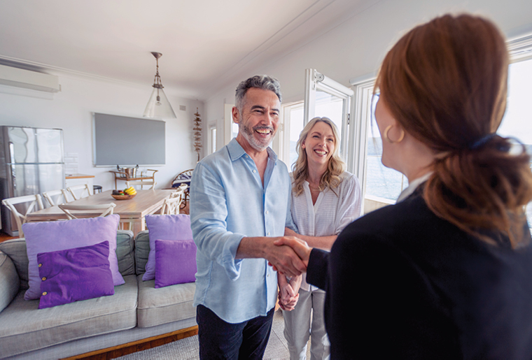 A couple smiling while using a laptop