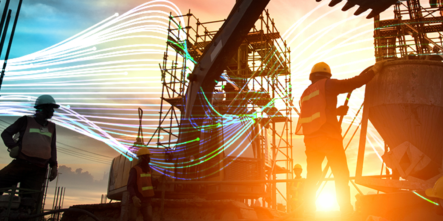 A man and woman in construction gear look at a tablet on site