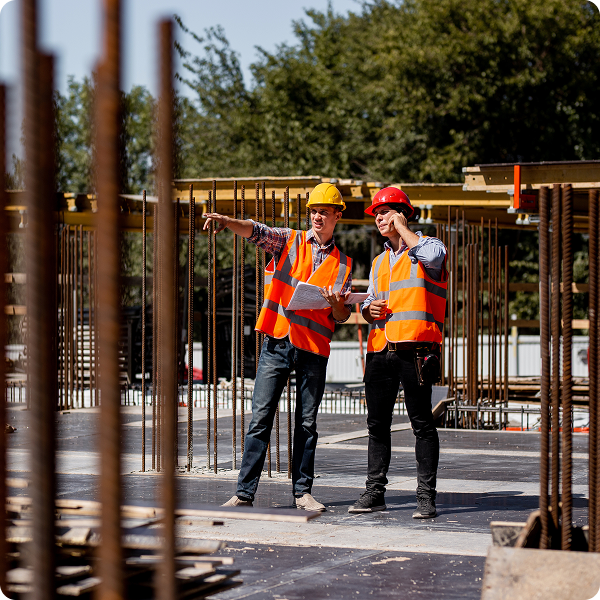 A construction worker points to the site while another talks on the phone