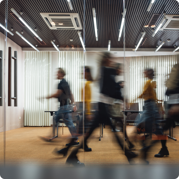 Workers in an office rush past each other in a blur.