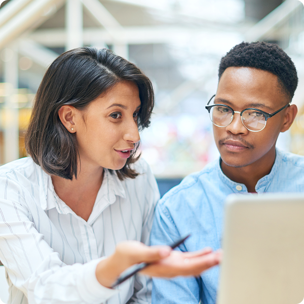 A male and female office worker discuss over a laptop.
