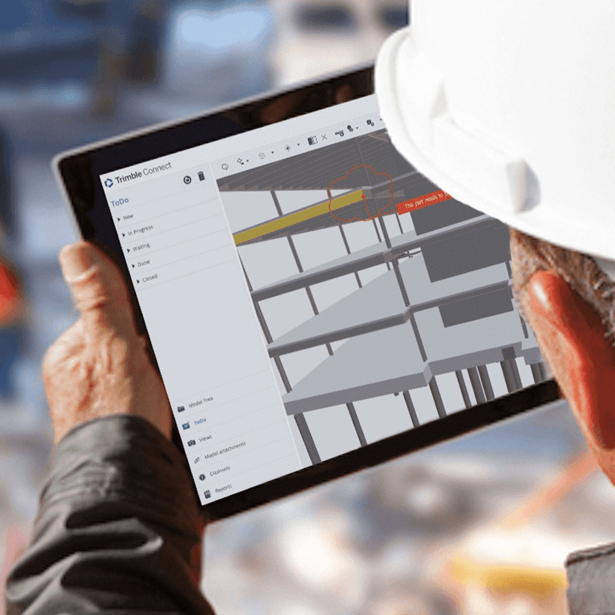 Kijk over de schouder vakman met Trimble connect op tablet op de bouwplaats