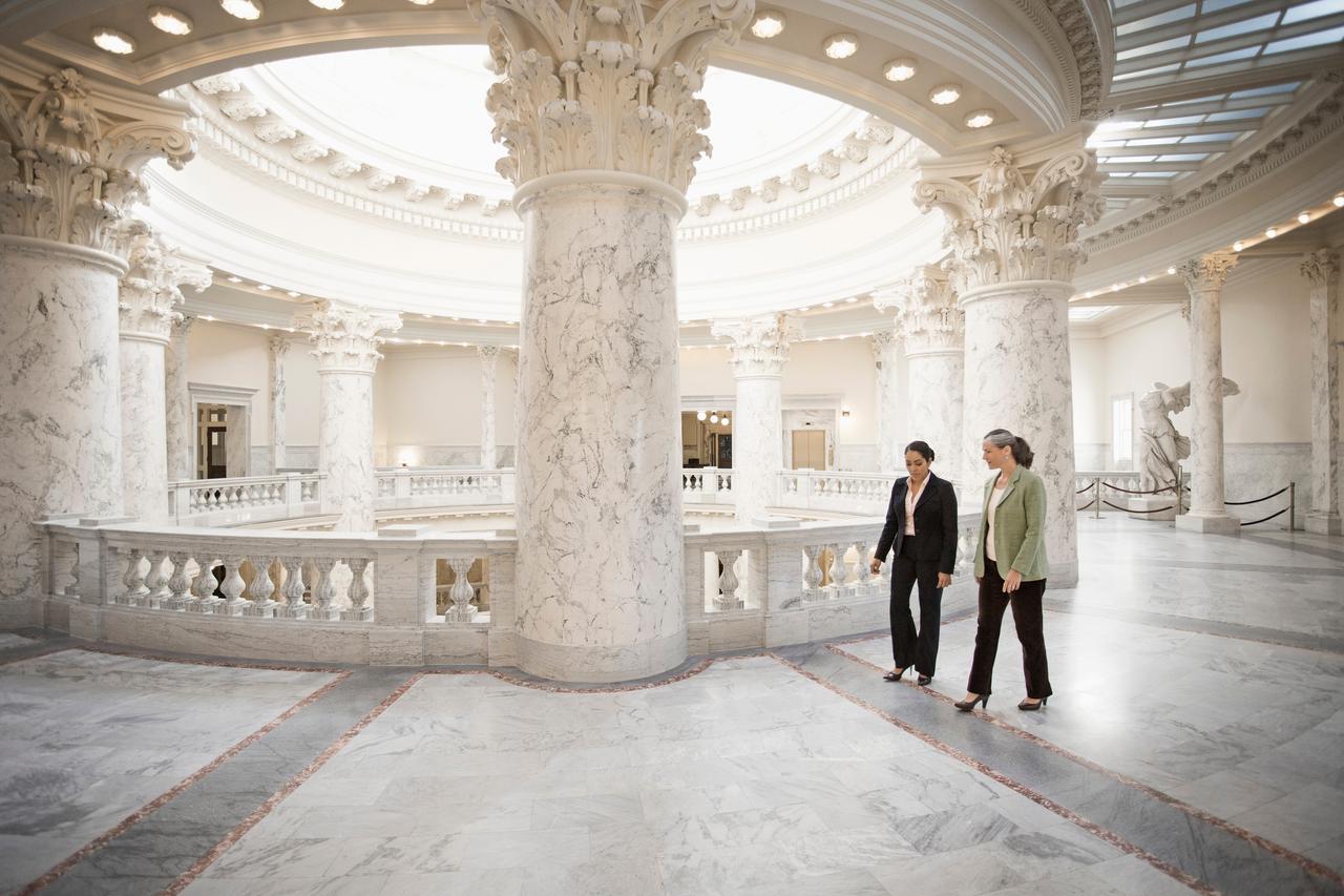 Two colleagues walking through an elaborate Federal building.