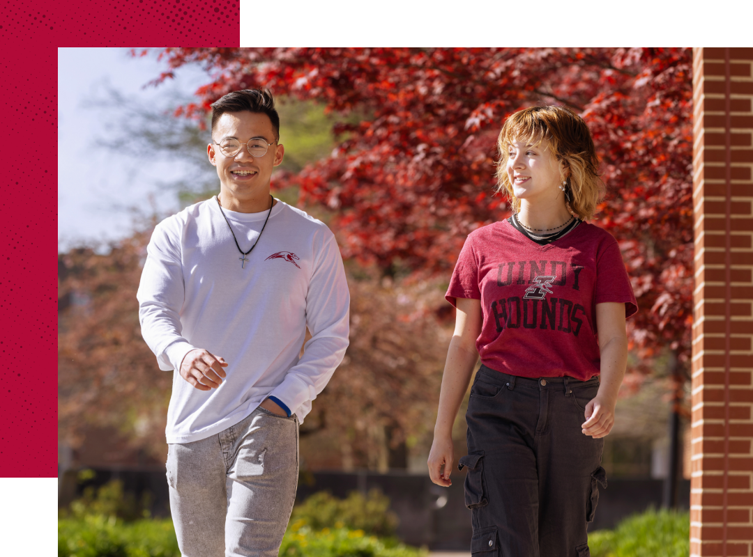Two students smiling and walking on campus