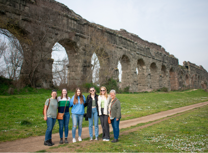 Students standing in front of aqueduct in Italy.