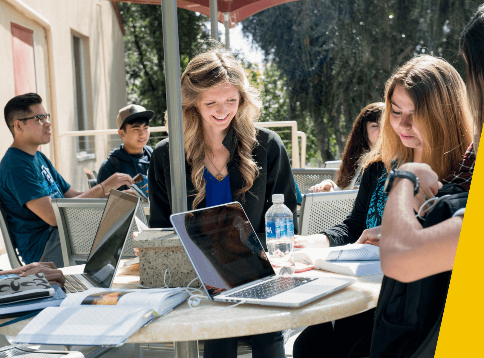 Students working on laptops outside.
