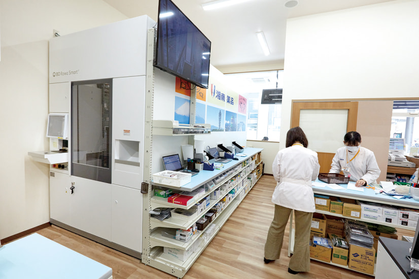 自動調剤機と薬剤師が働くモダンな薬局の内部。