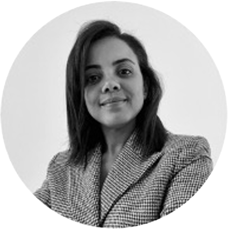 Black-and-white circular headshot of a smiling woman with shoulder-length dark hair wearing a checked blazer.