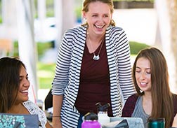 A group of female students or colleagues enjoying a moment of laughter and conversation outdoors.