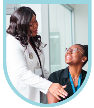 A happy doctor in a white coat talks to a smiling woman looking up at her.