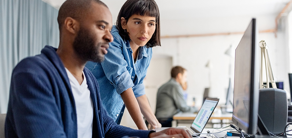 two people in corporate setting at desktop together