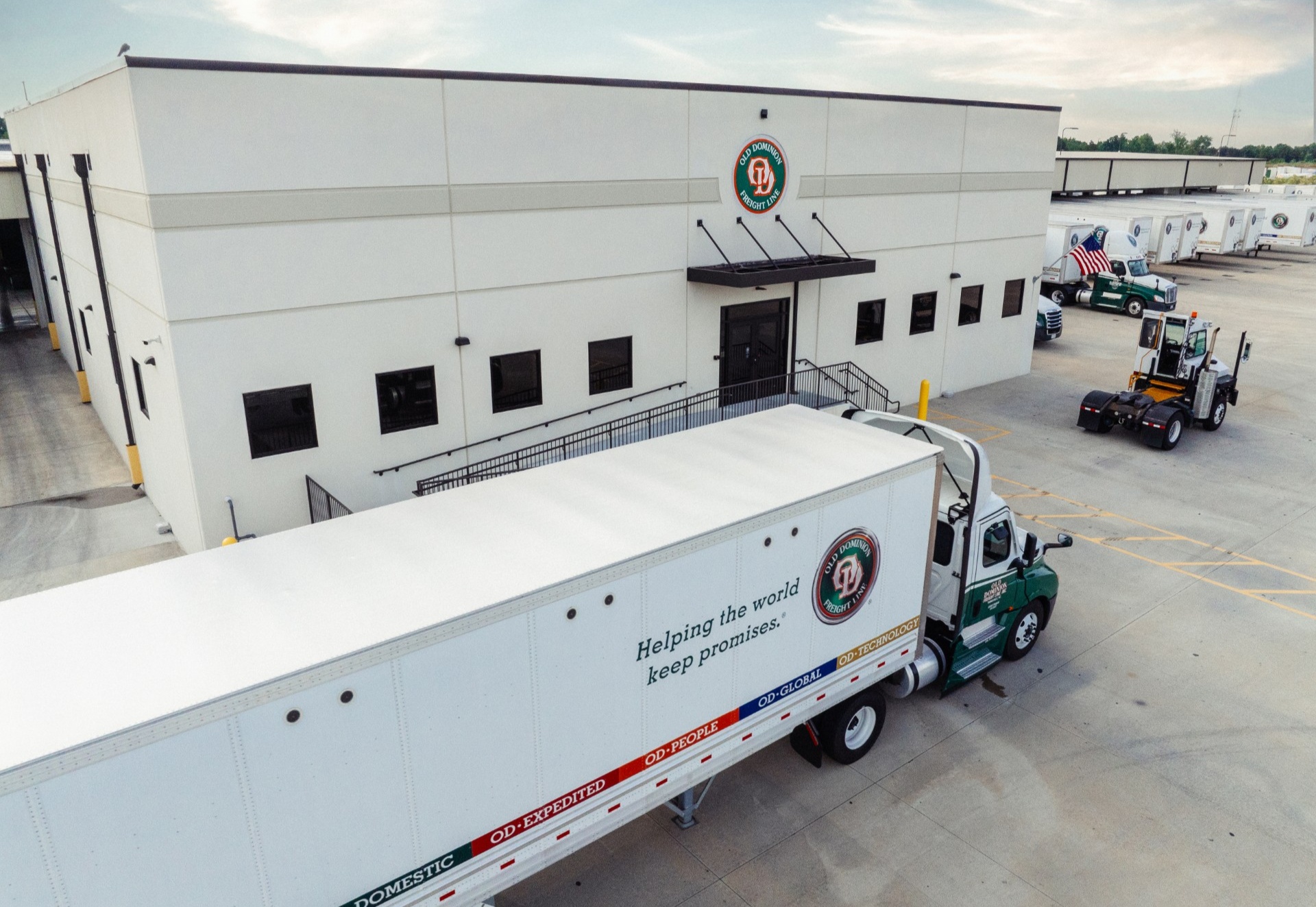 A white Old Dominion Freight Line building with a truck and trailer featuring the slogan 'Helping the world keep promises' and various service offerings.