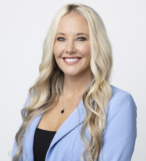 A smiling woman with long blonde hair wearing a light blue blazer.