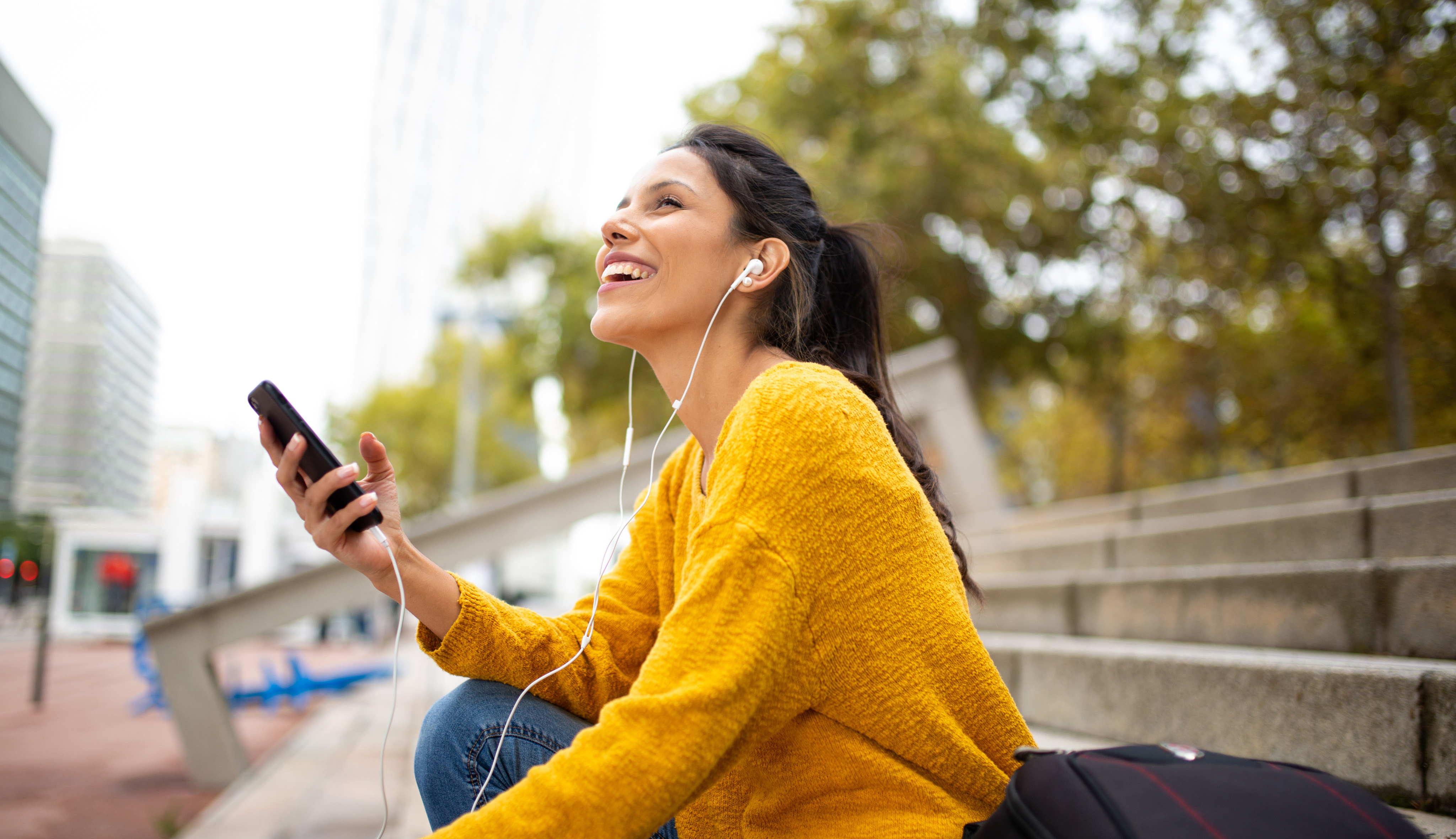 Woman wearing over-ear headphones checks her phone.