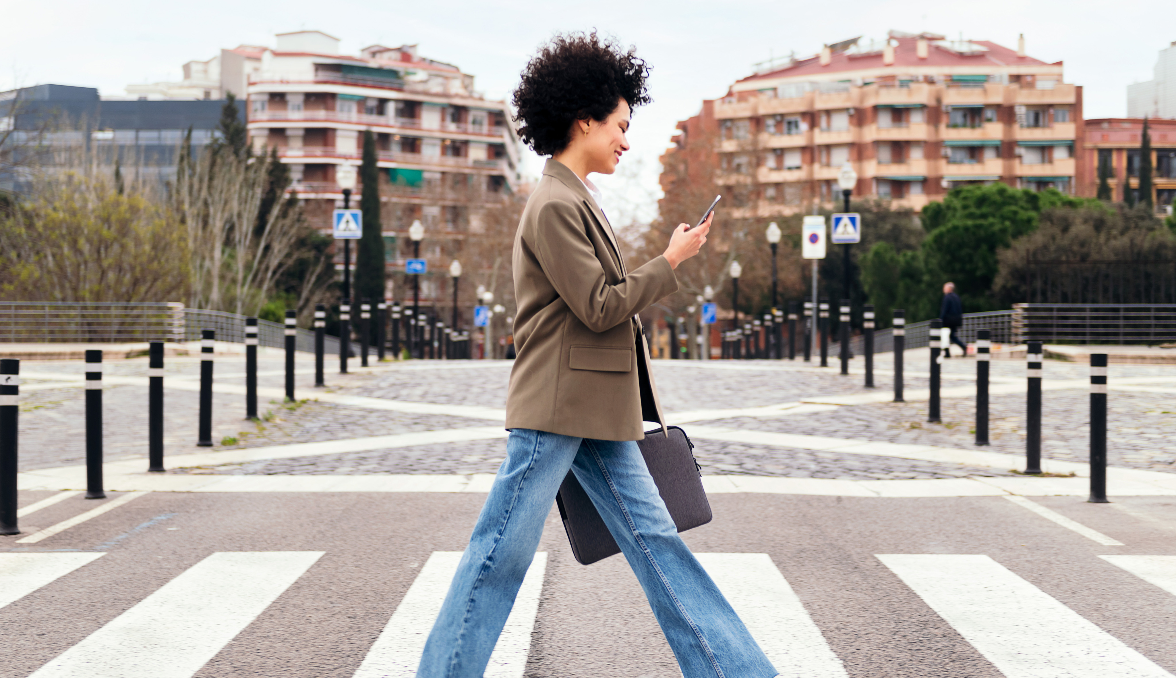 Woman wearing over-ear headphones checks her phone.