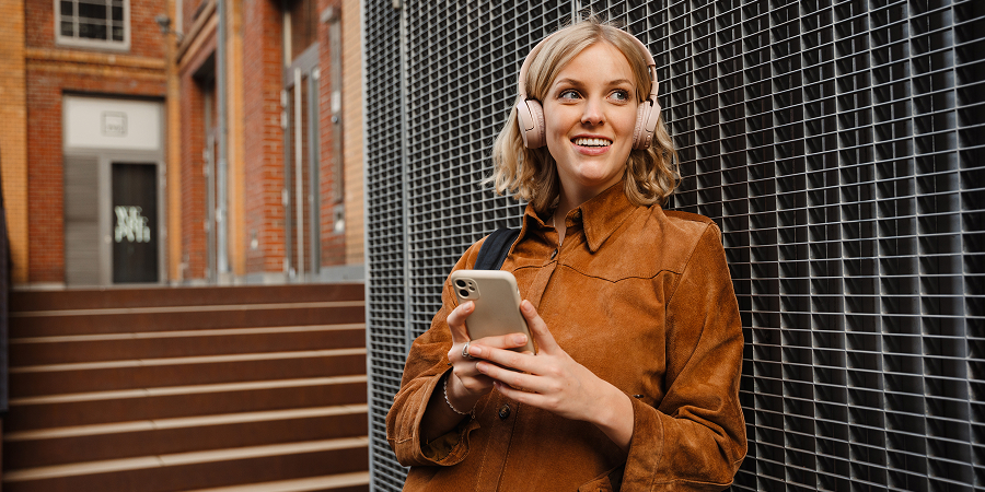 Woman wearing over-ear headphones checks her phone.