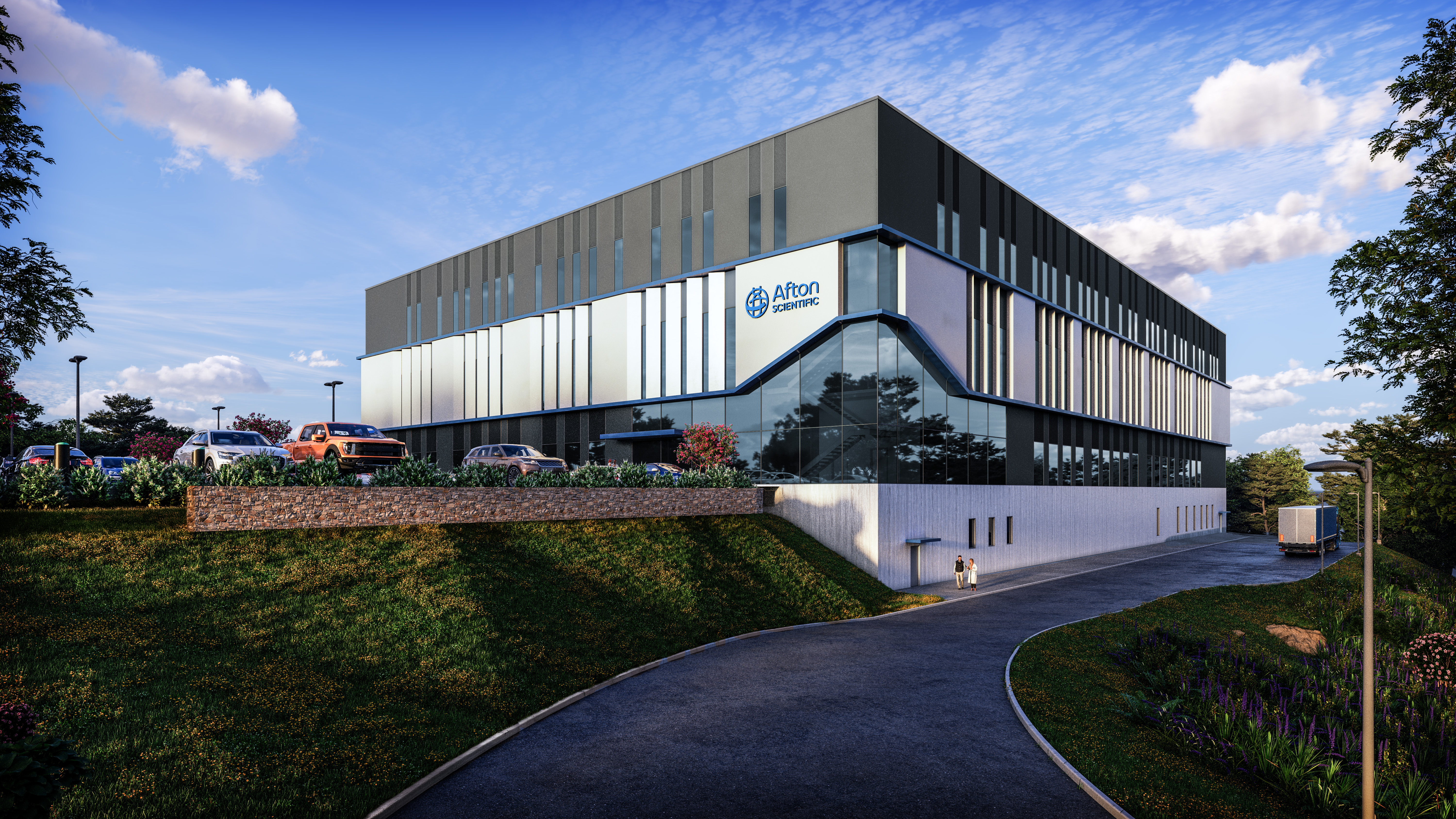 A modern, multi-story building with a grey and white facade and the "Afton Scientific" logo, surrounded by green landscaping and a parking area under a blue sky.