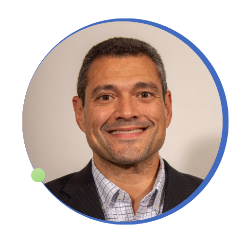 Headshot of a smiling man with short dark hair, wearing a checkered shirt and dark suit jacket.