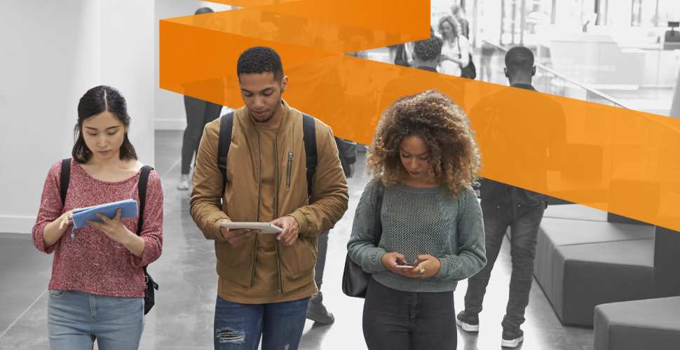 Three college students walking together, looking at their phones